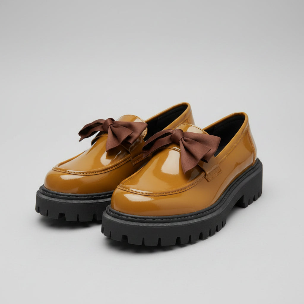Pair of mustard yellow shoes with brown bows on a textured surface