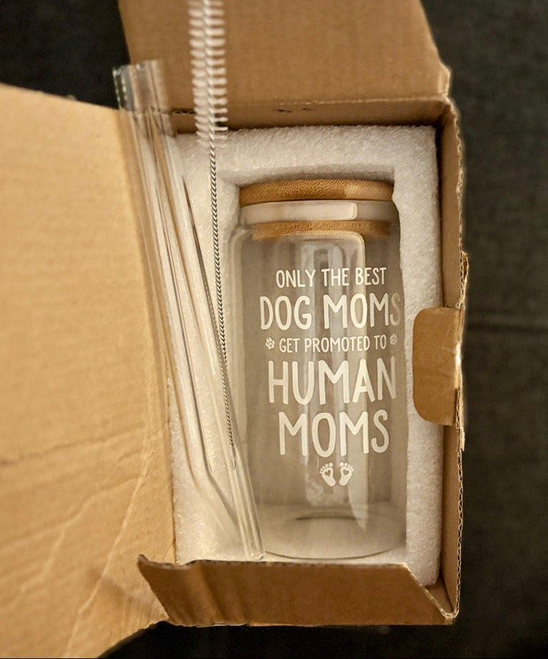 Glass jar with straw and text 'Only the best dog moms get promoted to human moms' in a cardboard box.