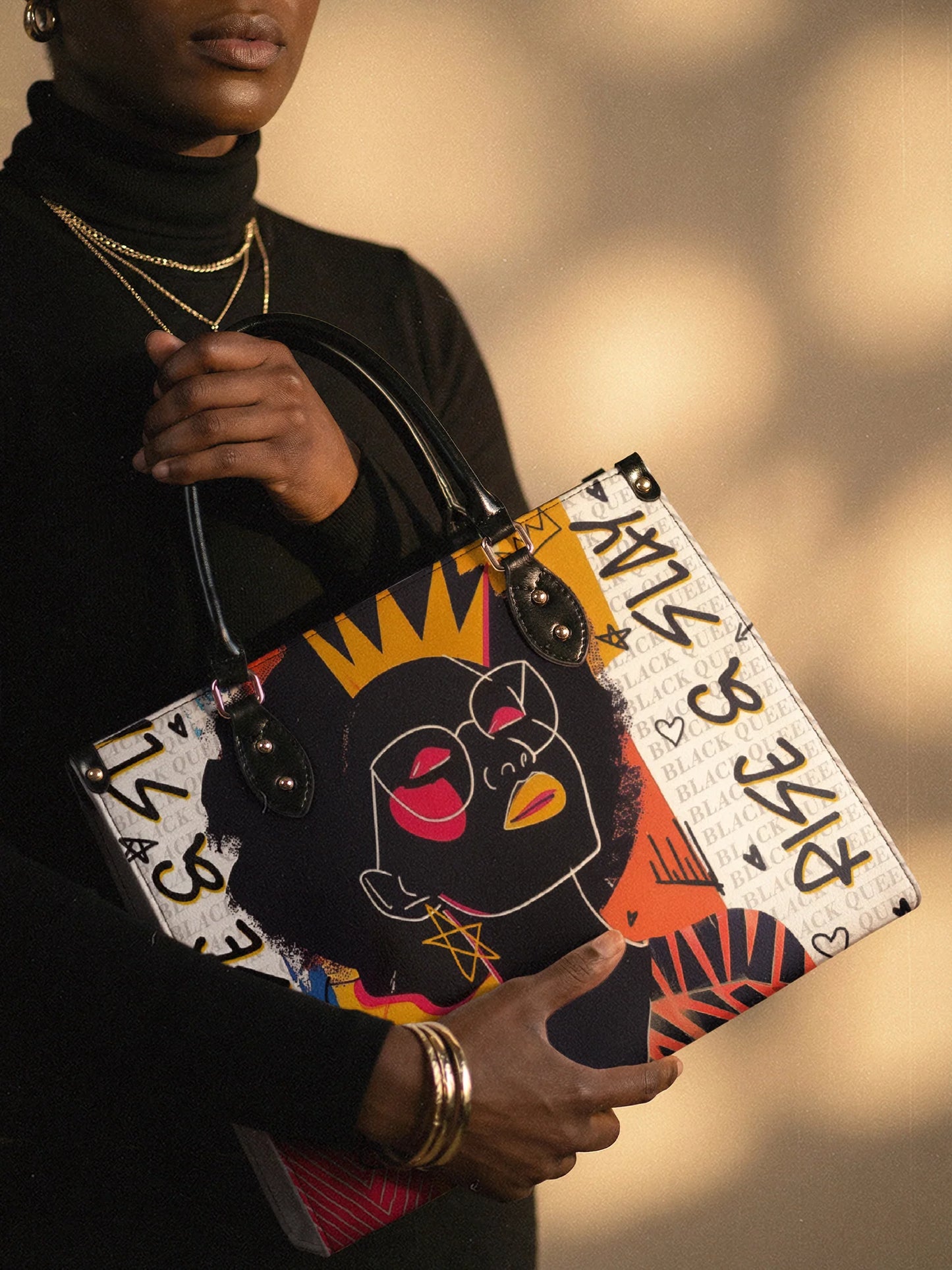 Person holding a colorful handbag with a stylized face design against a blurred background