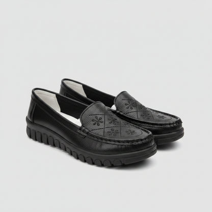Black loafers on a light-colored surface with a blurred background