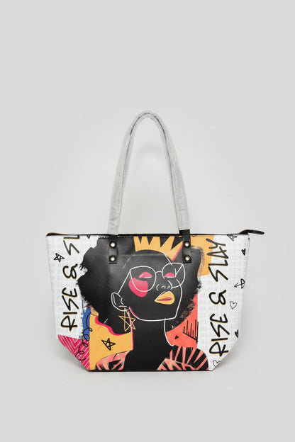 Handbag with artistic design of a face and text held by a person in an indoor setting.